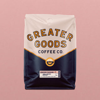 Lunar New Year Blend coffee bag by Greater Goods Coffee Co with a cream top, navy lower half, and a circular logo against a pink background
