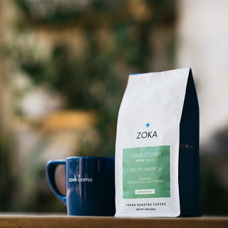 Zoka Decaf Tangletown coffee bag with a blue mug in the background.