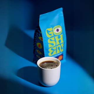 Blue Mokha Java bag angled in a blue lit room with a cup of coffee in front.