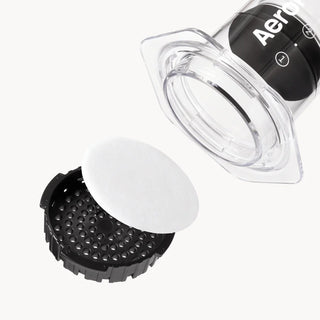 AeroPress filter assembly with a white round paper filter and black perforated basket