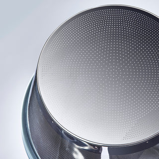 Close up of a circular perforated metal coffee filter with many tiny holes.