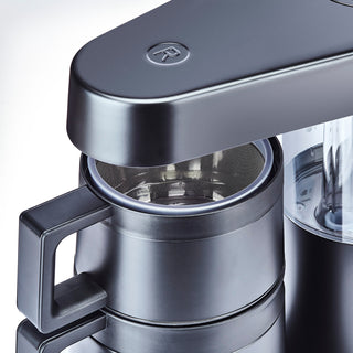 Close up of a black drip coffee maker with a metal mesh filter visible inside.