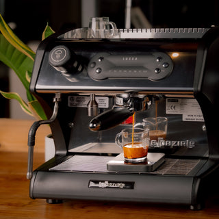 Espresso being pulled into a glass cup on a LUCCA espresso machine with crema on the surface