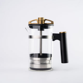 Close up of The BIRD coffee brewer top with bronze crown and black ring over a glass carafe