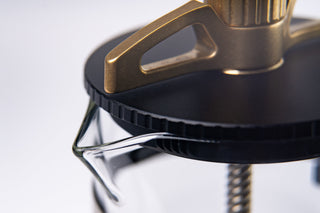 Person adjusts the piston mechanism of The BIRD using a braided metal rod over the glass carafe.