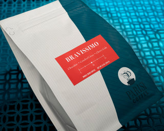 Bravissimo tasting notes card on a red label resting atop a lined notebook against a blue surface.