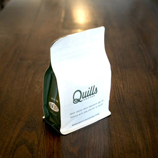 Night Owl coffee bag on a wooden table with a white tag showing Quills Coffee packaging.