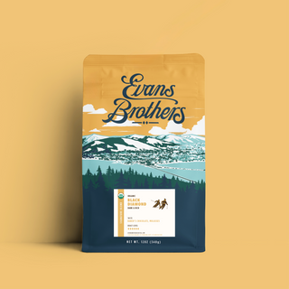 Black Diamond Blend coffee bag in dark navy packaging featuring rugged alpine landscape and trees