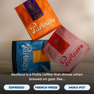 Three Bedford coffee bags from Partners Coffee Roasters arranged diagonally in orange blue and pink packaging.