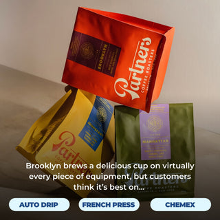 Red Brooklyn coffee bag resting atop yellow and green coffee bags.