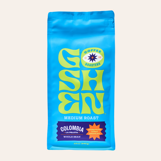 Blue Colombia La Pelota whole bean coffee bag with purple label and a stone fruits citrus chocolate badge