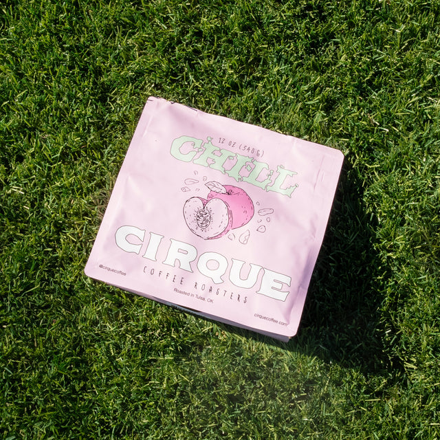 Chill pink coffee bag resting on grass, part of Cirque Coffee Roasters rotating single origin lineup