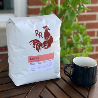 Close-up of a white Red Rooster Funky Chicken Decaf coffee bag with red rooster logo and pink label
