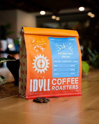 Bright orange Afterlight decaf coffee bag with a blue label and sun graphic.