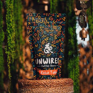 Unwired Coffee bag with bright abstract artwork on a surface beside greenery and hanging decor.