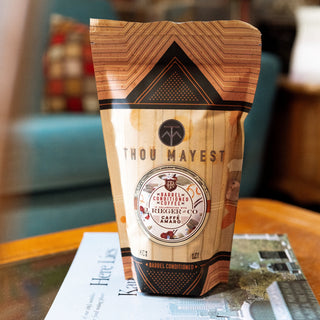Barrel conditioned coffee bag for Caffè Amaro with Thou Mayest branding and bold orange and black geometric pattern.