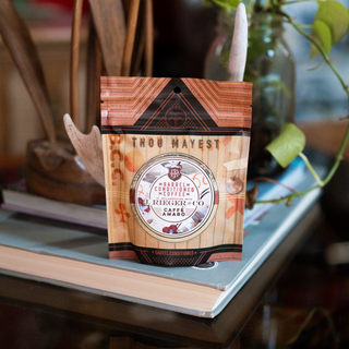 Barrel conditioned coffee bag with Thou Mayest Caffé Amaro branding on a shelf.