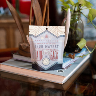 Laid Back Decaf coffee bag with geometric label nestled among wooden utensils.