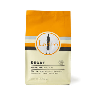 Ladro Decaf coffee bag on kraft packaging with orange top and circular Ladro logo.