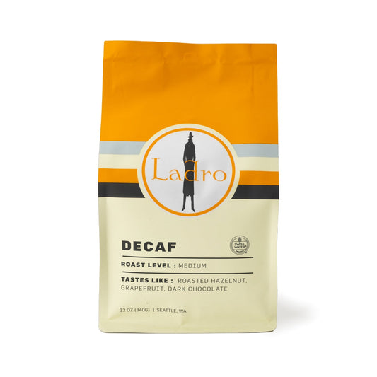 Ladro Decaf coffee bag on kraft packaging with orange top and circular Ladro logo.
