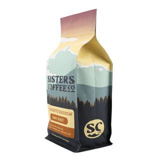 Sisters Coffee Black Butte Gold Decaf bag with pastel mountain illustration and logo.