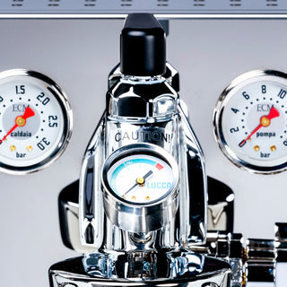 Close up of ECM Synchronika espresso machine front with dual gauges flanking a chrome group head and the LUCCA flow gauge at the base.