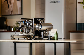 ECM Technika VI espresso machine on a counter with a Mazzer grinder and Verve coffee bag in the background.