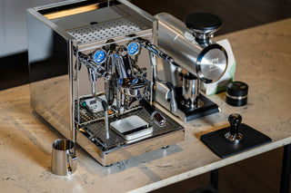 Close view of ECM Technika VI front with blue gauge dials and chrome portafilters.