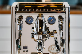 Close-up of the ECM Technika VI front with blue pressure gauges and chrome portafilters.