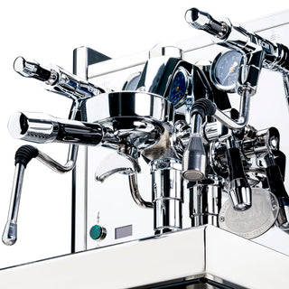 Angled close-up of the chrome ECM Technika VI espresso machine showing central group head blue gauges and surrounding hardware