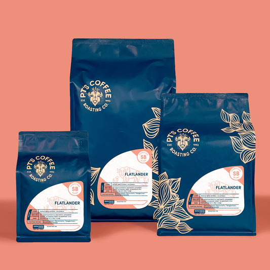 Blue Flatlander coffee bags labeled Signature Blend arranged against a peach background