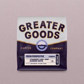 Close-up of a Greater Goods coffee bag showing bold typography and a cup logo on a pink backdrop