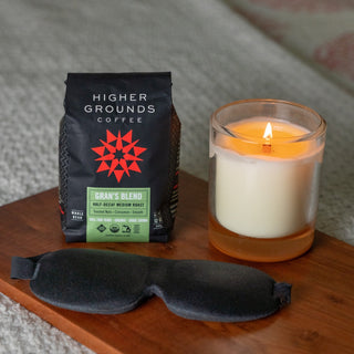 Gran's Blend Half-Decaf coffee bag from Higher Grounds on a wooden table beside a lit candle.