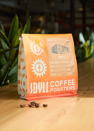 Idyll coffee bag from Idyll Coffee Roasters on a wooden table with roasted beans nearby