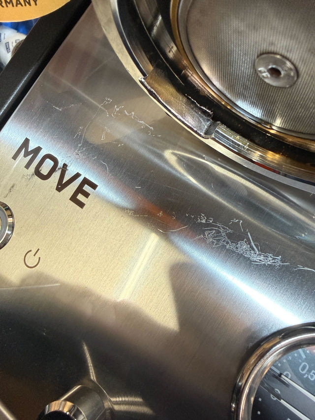 Close up of Profitec MOVE espresso machine metal surface with scratches and part of the pressure gauge.