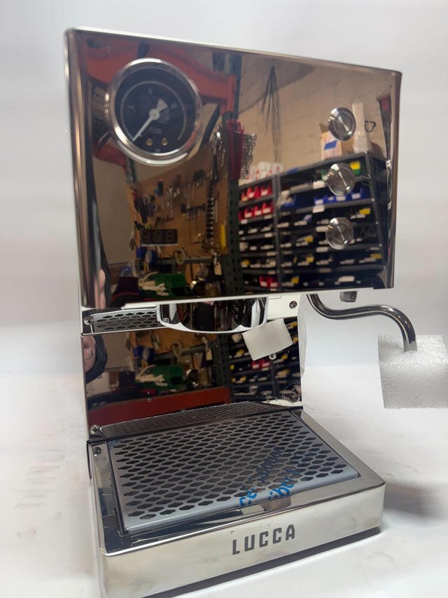 Open box Lucca Tempo espresso machine with chrome front panel and round gauge reflecting a workshop