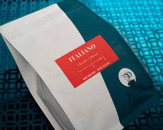 Parisi Italiano coffee bag with bold red Italiano label on a teal surface beside a notebook