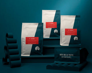 Three L Alba coffee bags arranged on a teal backdrop with red labels visible