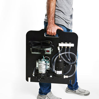 Person holding a collapsible mobile espresso cart panel with mounted hardware and hoses.