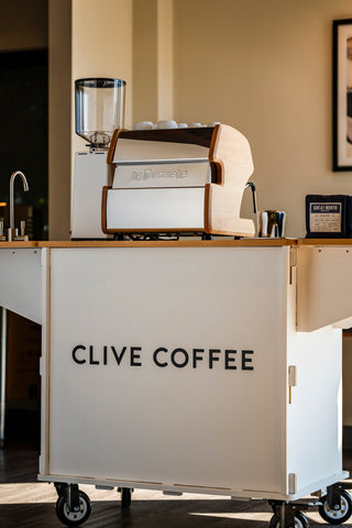 LUCCA A53 Direct Plumb espresso machine on a counter with white mugs on top and CLIVE COFFEE branding.