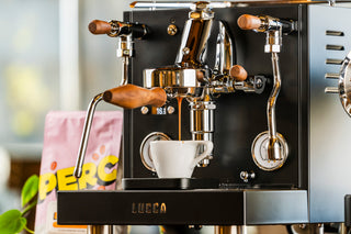 LUCCA espresso machine with dual groups wood handles and a white cup beneath