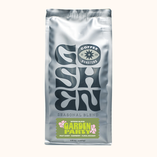 Close up of a shiny silver coffee bag with a bold logo and round roast emblem on a light background.