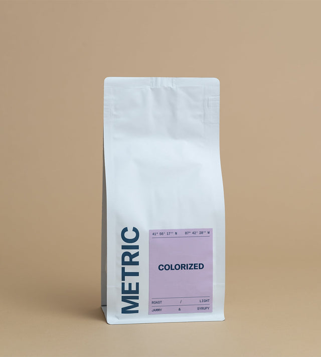 Colorized coffee bag with lavender label on a white standup pouch against a tan backdrop