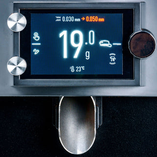 Close up of Mahlkönig E65W GbS espresso grinder display showing 19 g dose and portafilter slot