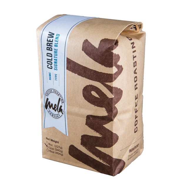 Kraft paper coffee bag wrapped with a light blue label reading Cold Brew Blend from Mela Coffee.