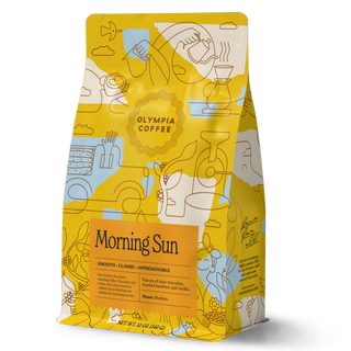 Morning Sun coffee bag with yellow and teal abstract pattern rests against a green background with a Morning Sun label.