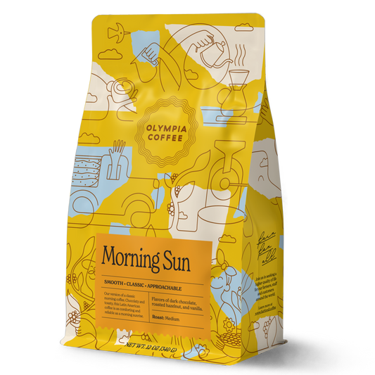 Morning Sun coffee bag with yellow and teal abstract pattern rests against a green background with a Morning Sun label.