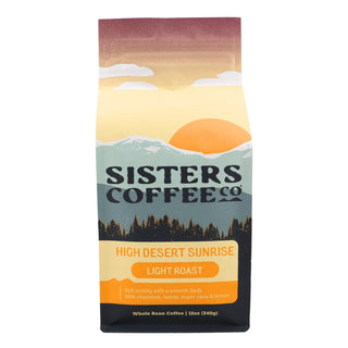 Front view of a Sisters Coffee High Desert Sunrise bag featuring a sunrise and mountain landscape