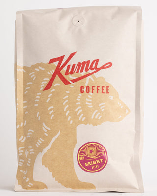 Kraft coffee bag angled forward with red script logo and Bright Blend badge visible.