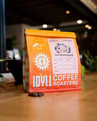 Bright orange La Bastilla Geisha Blend coffee bag on a wooden surface